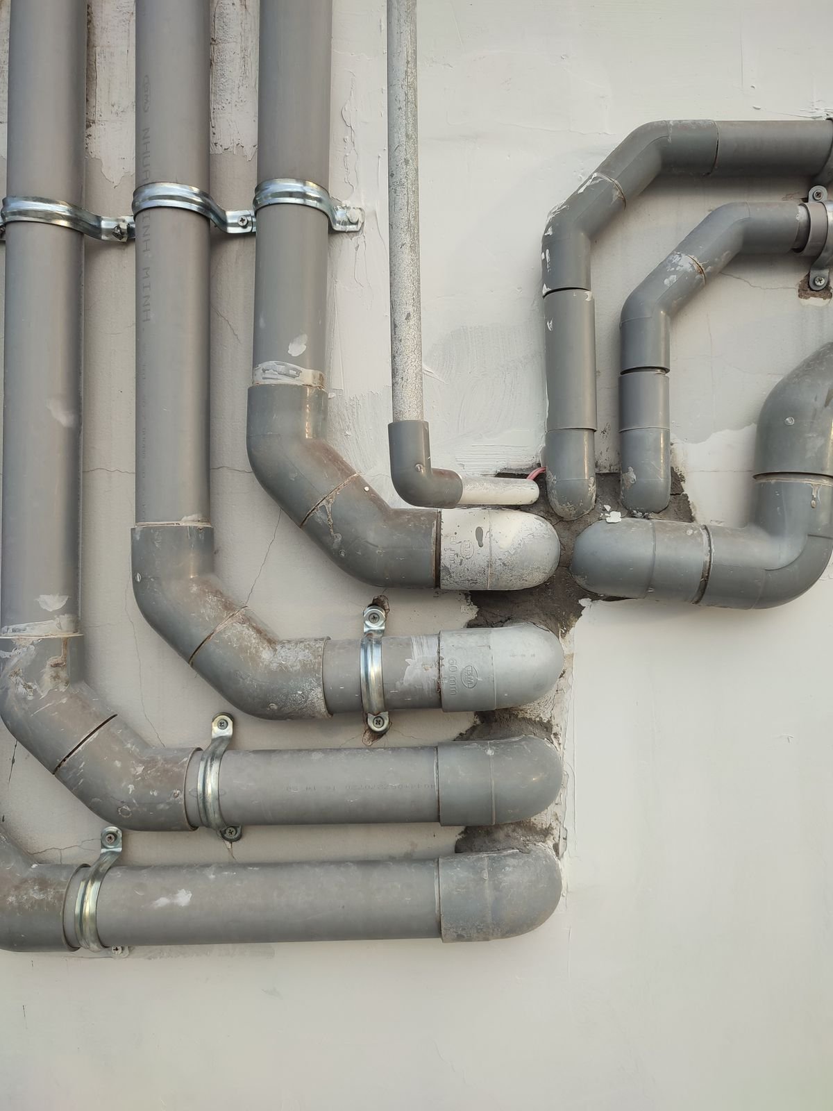 Interconnected gray metal pipes on a wall