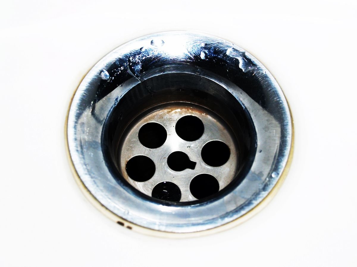 Chrome sink drain close-up with water droplets